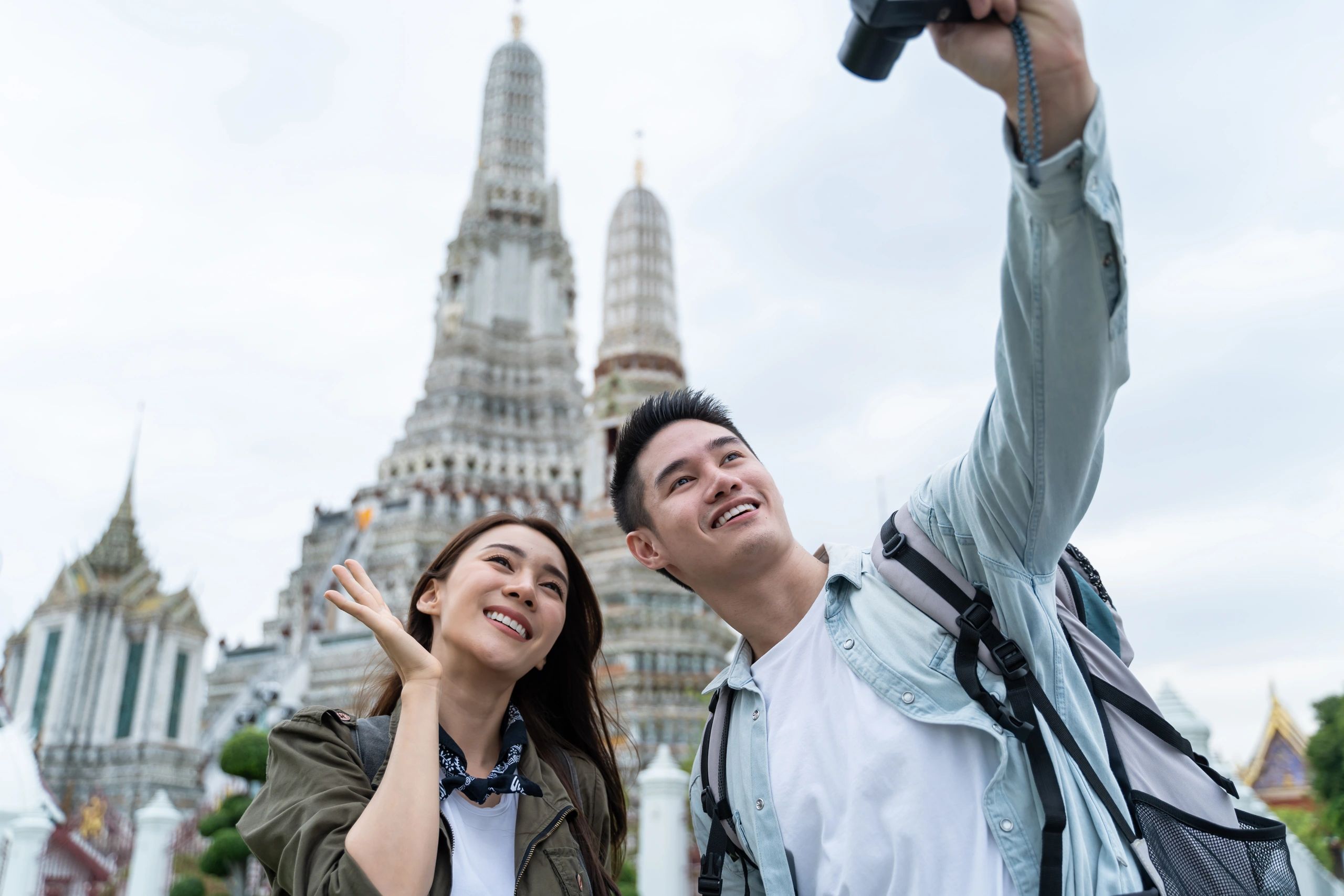 Asian couple backpacker using camera selfie and take